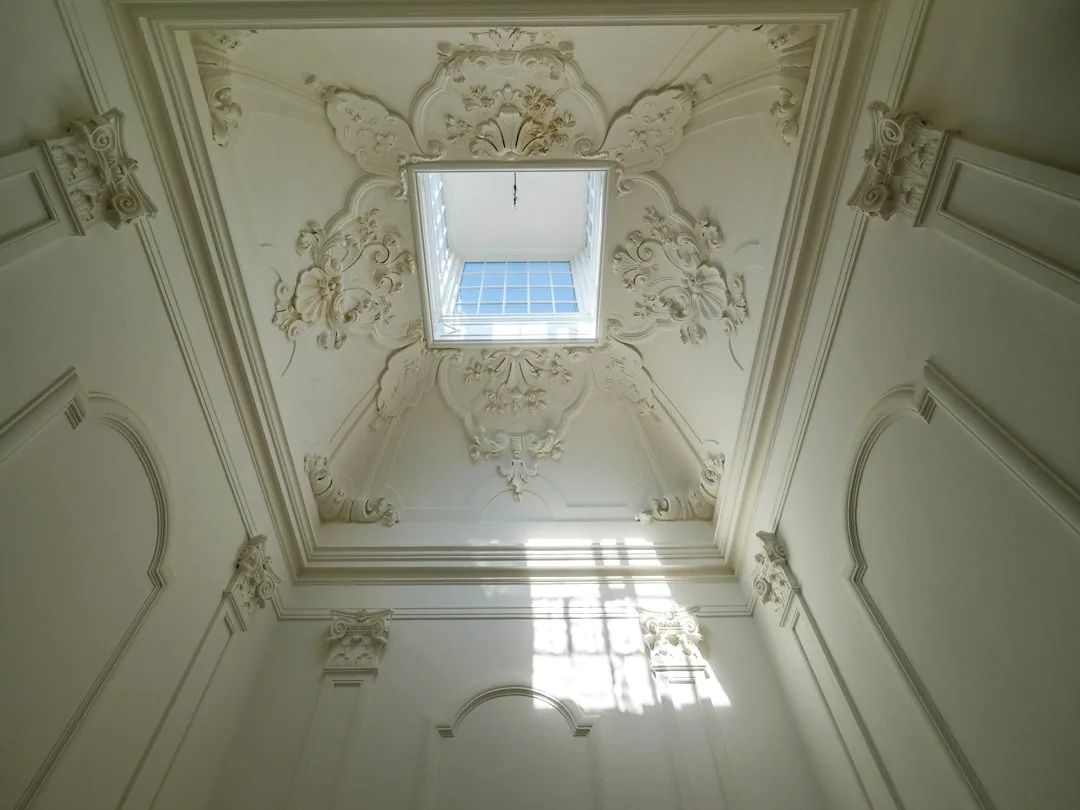 Een wit plafond met sierlijke ornamenten. — illustratieve foto