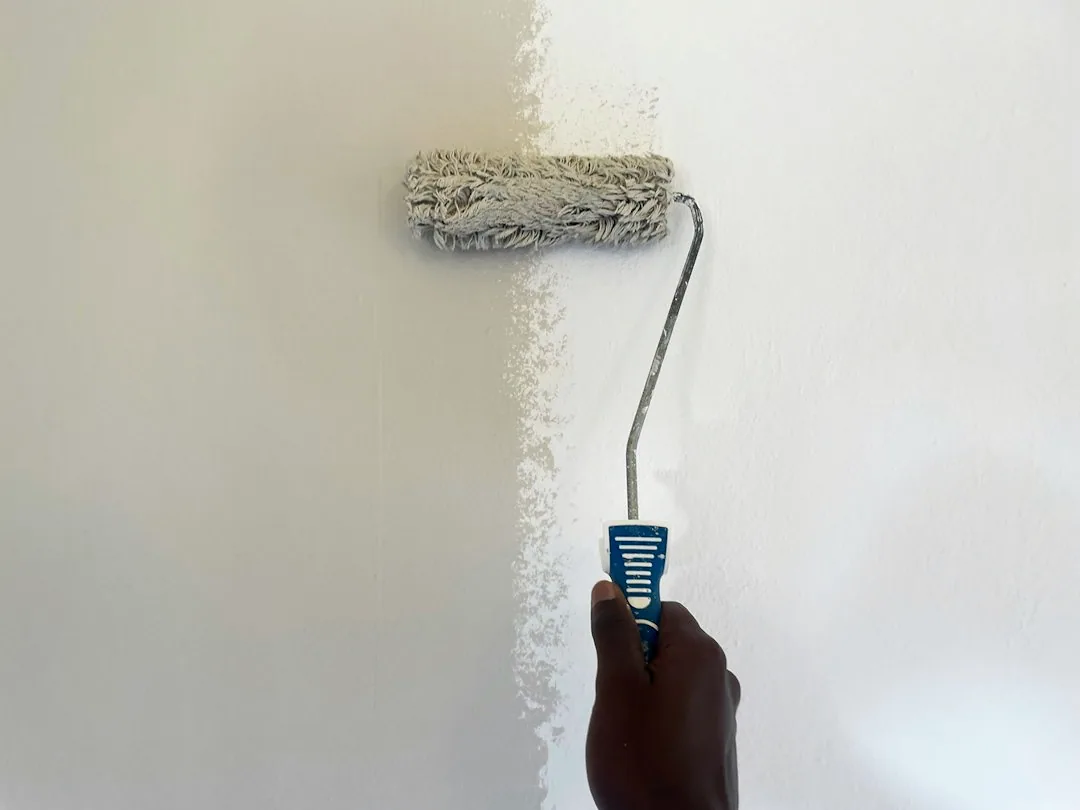 Een hand brengt met een roller verf op een wand aan. — illustratieve foto