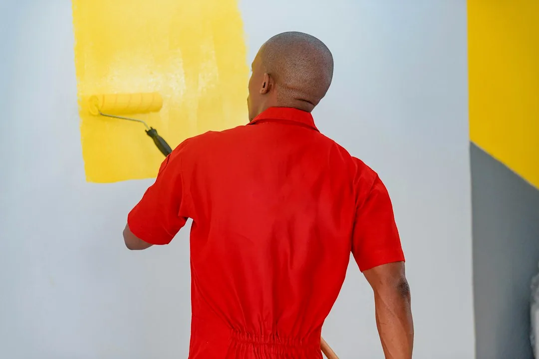 Een schilder brengt gele verf op een wand aan. — illustratieve foto