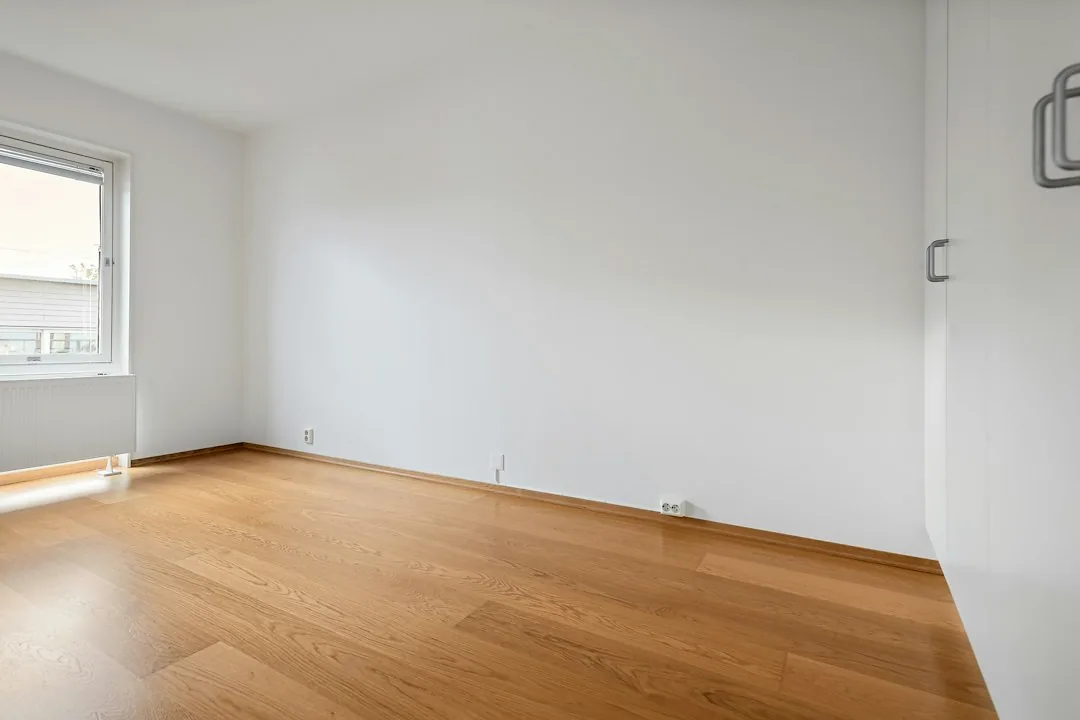 Een lege kamer met witte wanden en een houten vloer. — illustratieve foto