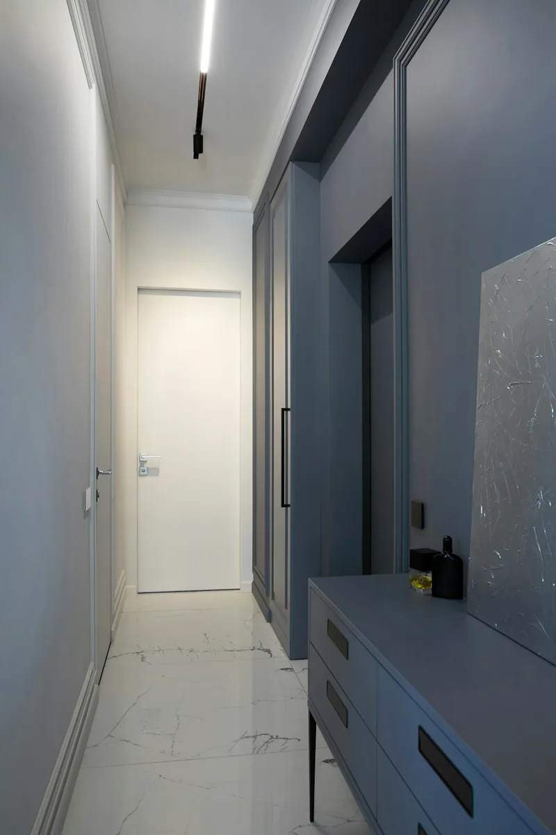 Een smalle hal met plafondverlichting en afgewerkte wanden. — illustratieve foto