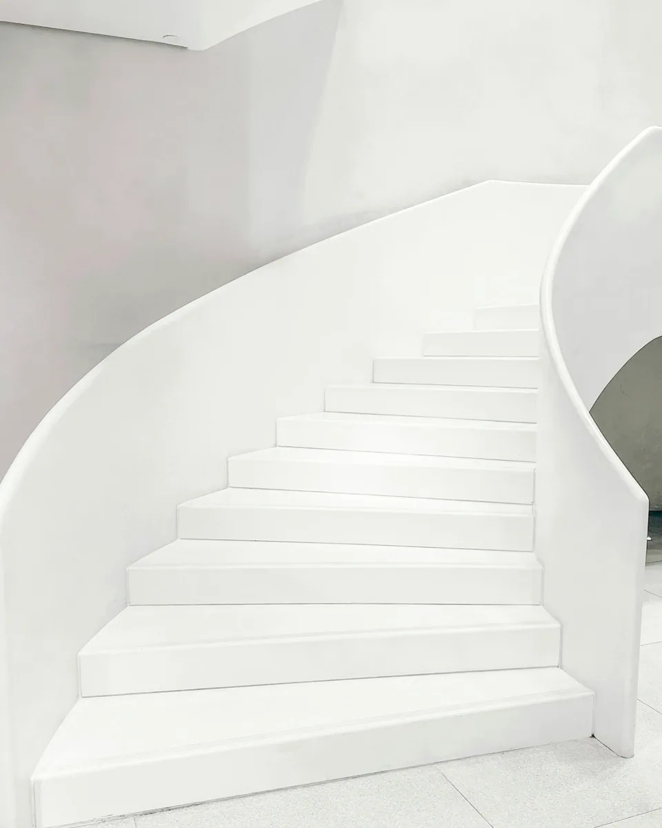 Interior inspiration: a white curved staircase with continuous wall lines.