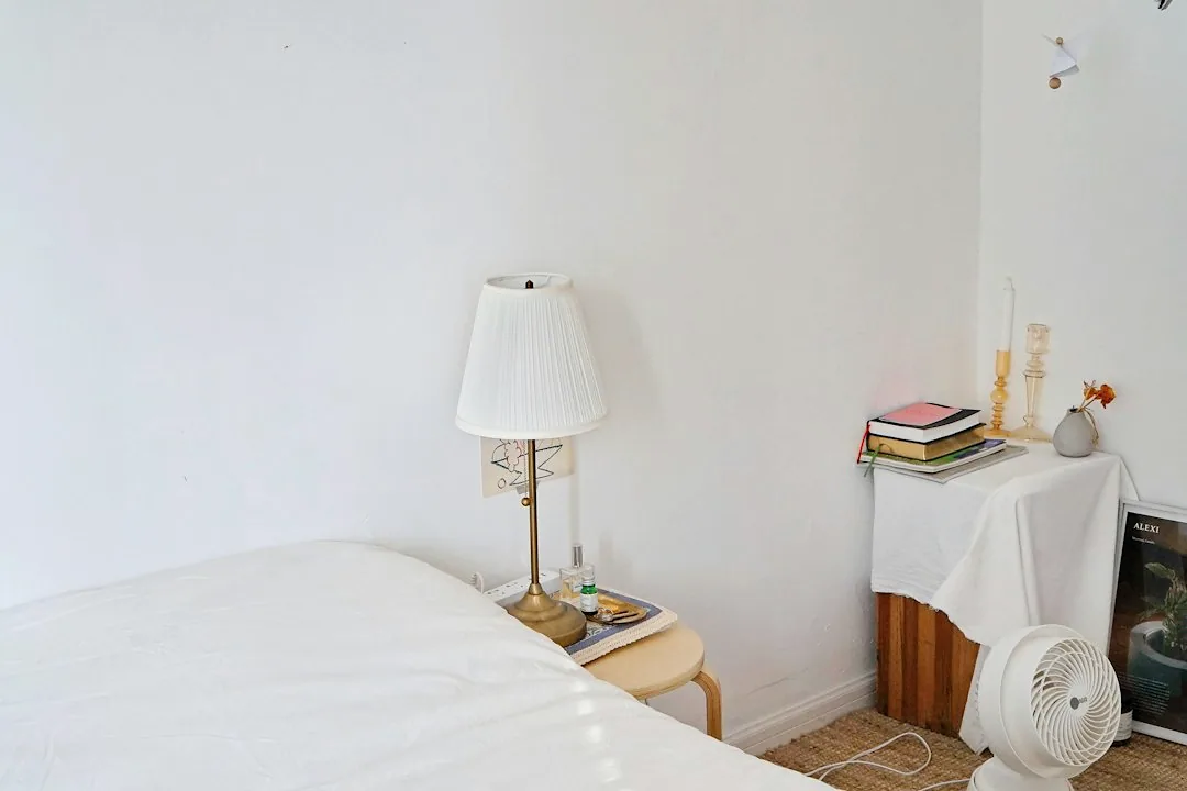 Een nachtkastje en lamp voor een witte slaapkamerwand. — illustratieve foto