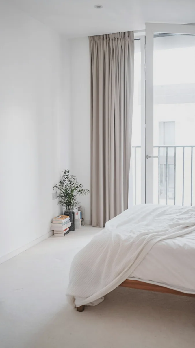 Een slaapkamer met lichte wanden en lange gordijnen. — illustratieve foto