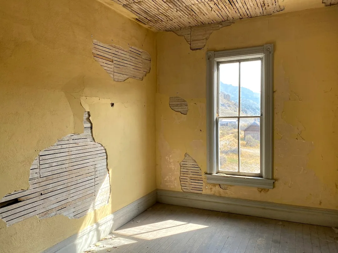 Een lege kamer met plaatselijk losgelaten wandafwerking. — illustratieve foto