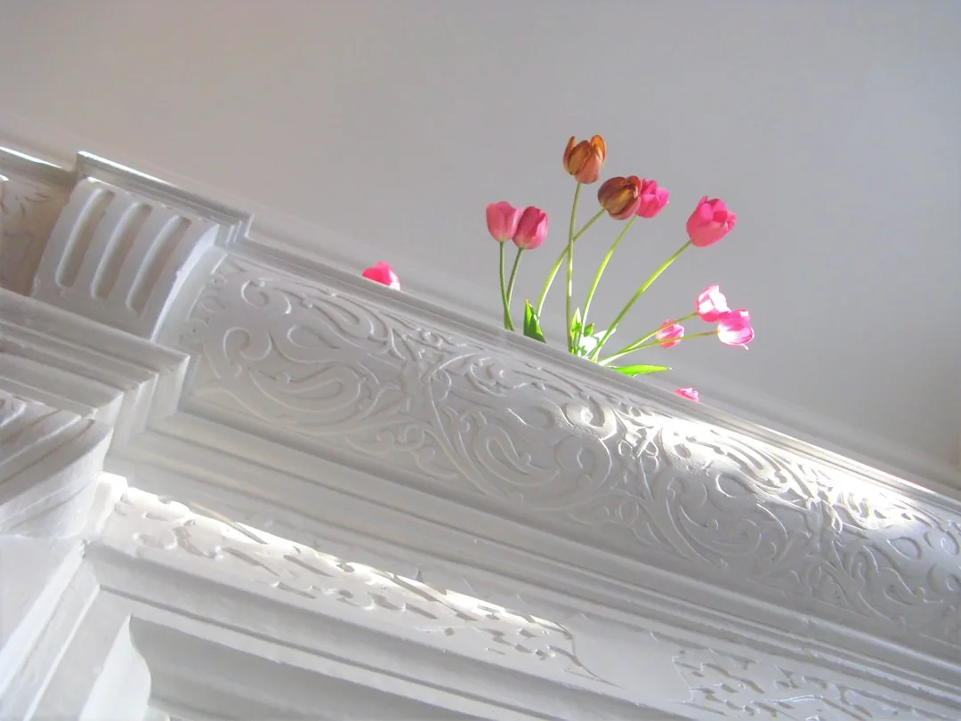 Een witte sierlijst met bloemen in de voorgrond. — illustratieve foto